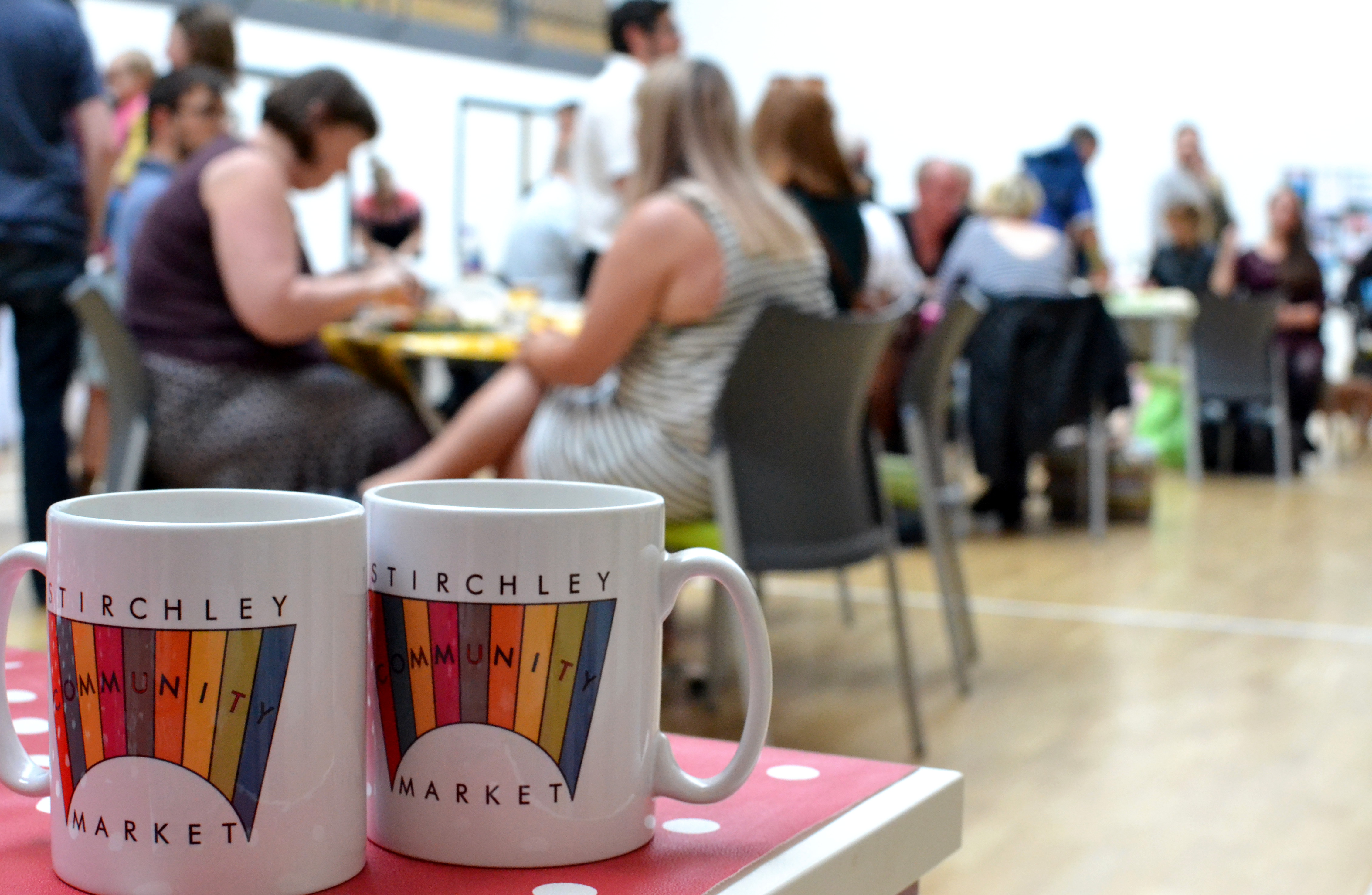 Market mugs in the foreground, and customers sitting around tables in the background