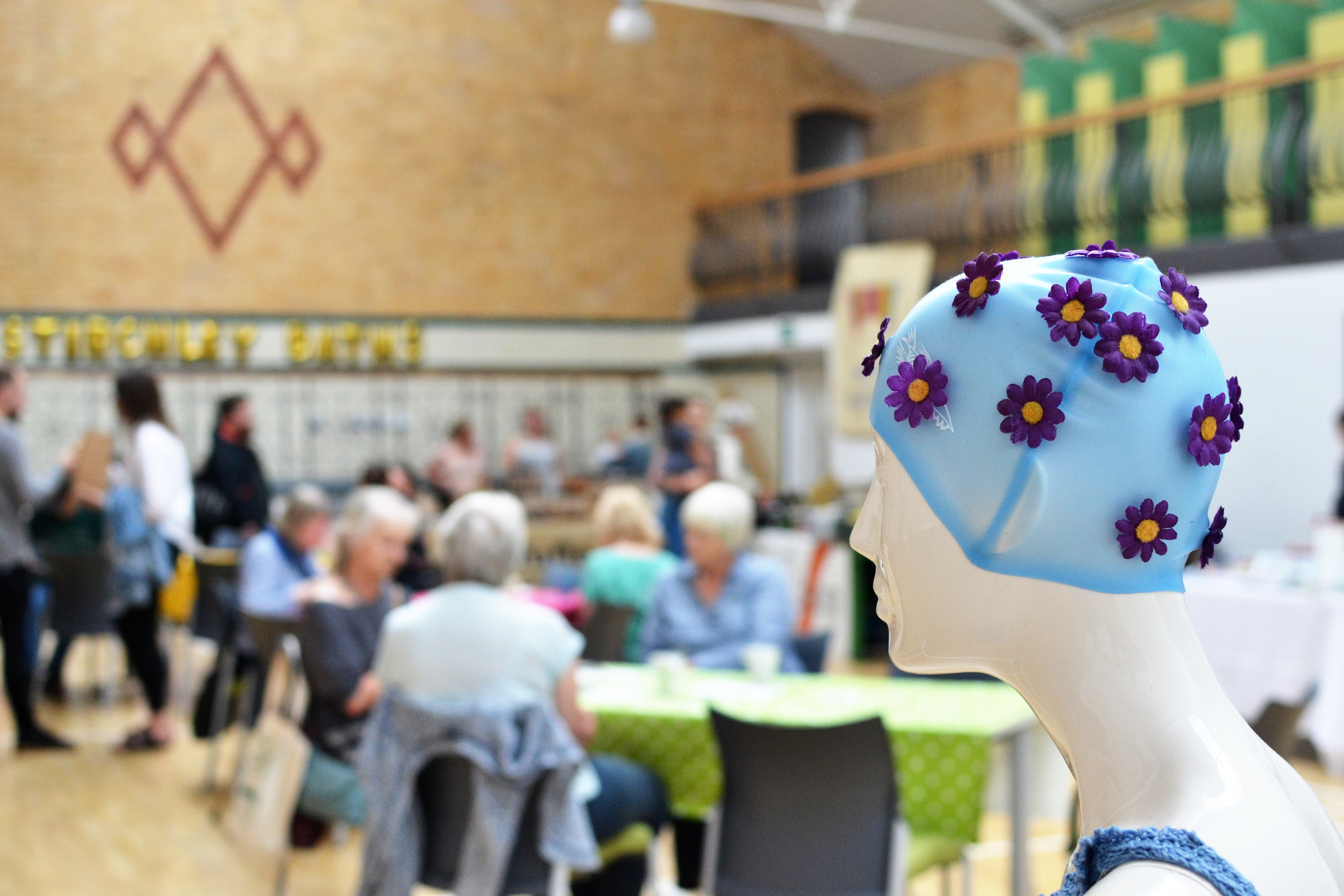 A dummy wearing a swimming cap looks out on Market taking place in the main hall